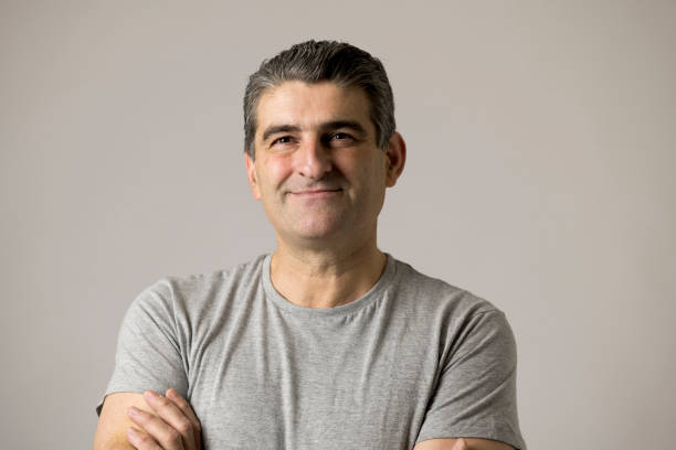 portrait of mature white man 40 to 50 years old smiling happy showing nice and positive face expression with folded crossed arms isolated on grey background in feelings and emotions concept